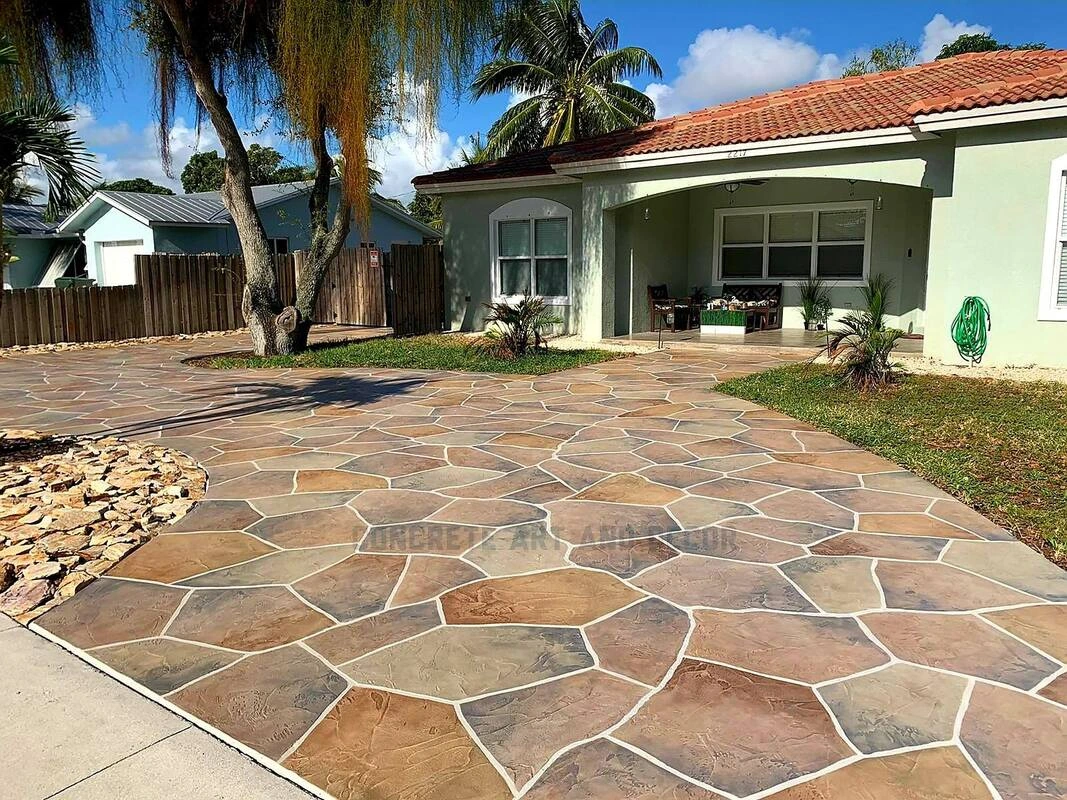 Custom stamped concrete in Southlake TX featuring a natural flagstone pattern in warm earth tones, creating an elegant driveway and entrance area for a Mediterranean-style home with terra cotta roof.